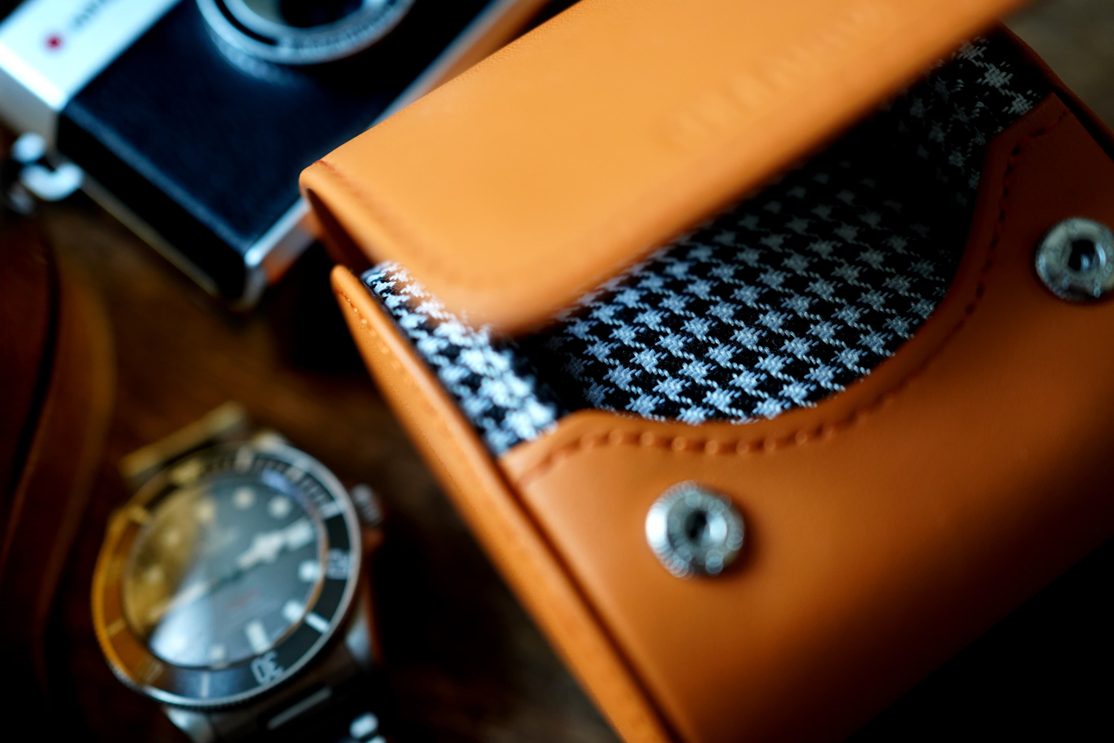 Unveil timeless elegance with our Icon Watch Case, a harmonious blend of style and protection. Crafted with an alluring Orange Leather exterior and a refined Houndstooth Cotton interior, this case redefines luxury. In this striking image, our Icon case takes center stage against a textured beige rock wall. The contrast of the case's sophistication and the rugged backdrop creates a captivating visual narrative. As you consider this masterpiece, imagine the perfect sanctuary it provides for your cherished watches, seamlessly combining fashion and functionality. Experience the iconic essence of watch storage like never before.