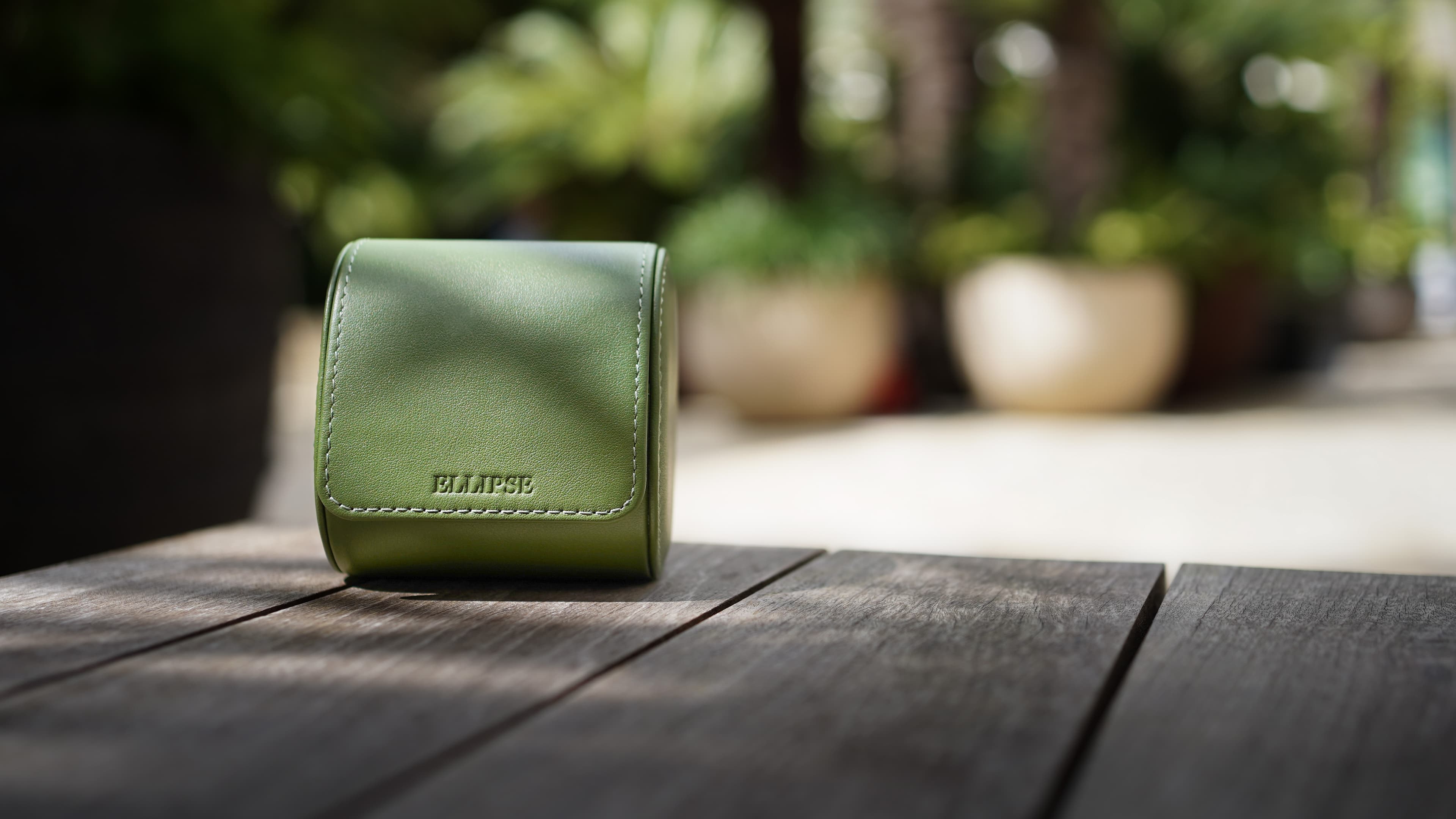 Our luxury evergreen case, held open in front of a kensington townhouse, featuring top green green leather and a chevron grey and white interior. The watch case contains a tudor watch,